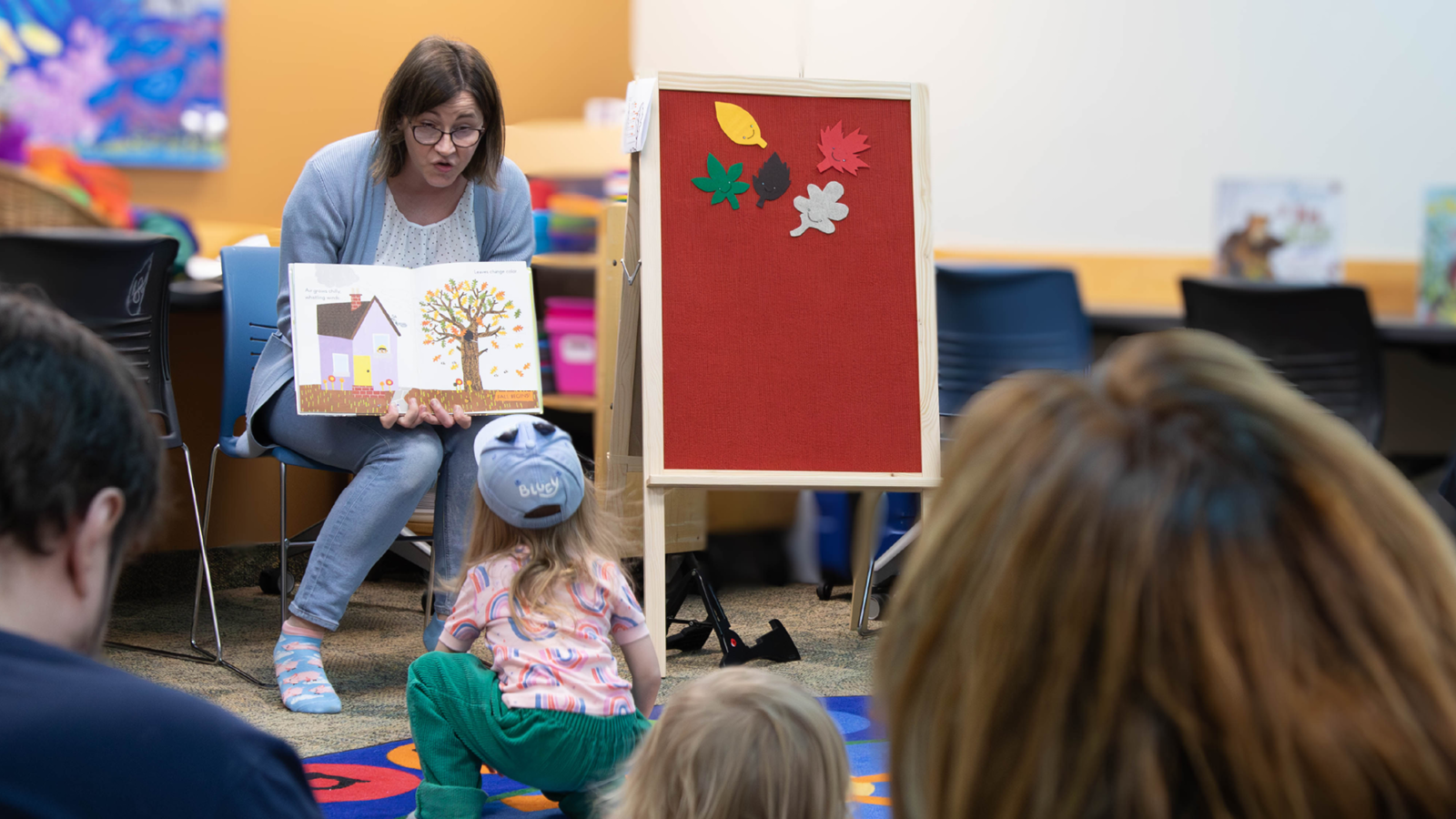Agata sitting in chair reading a picture book during storytime